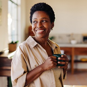 Woman smiling while enjoying cup of tea at home