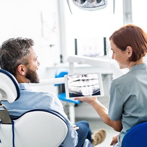 Smiling dental assistant and patient looking at X-ray