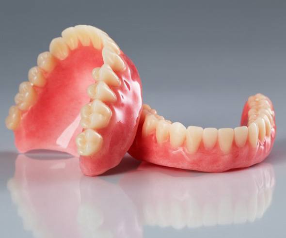 Two dentures sitting on a clear surface