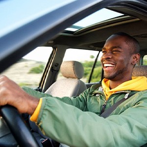 Man smiles while driving to dentist’s office