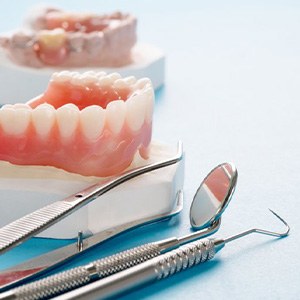 Dentures resting on a display next to dental tools