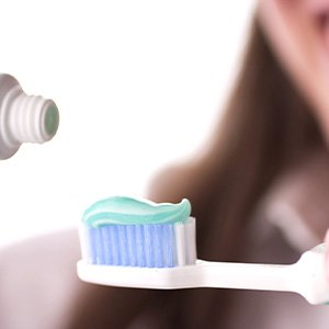 Lady puts toothpaste on brush