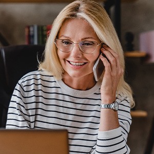 Woman with glasses smiling while talking on phone