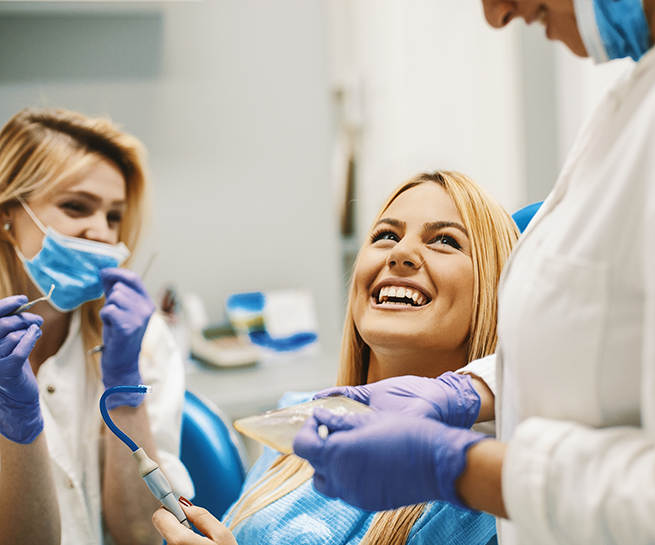 Woman in the dental chair looking up and grinning at her dentist