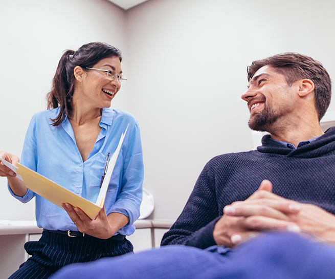 Dental team member laughing with a patient in the treatment chair