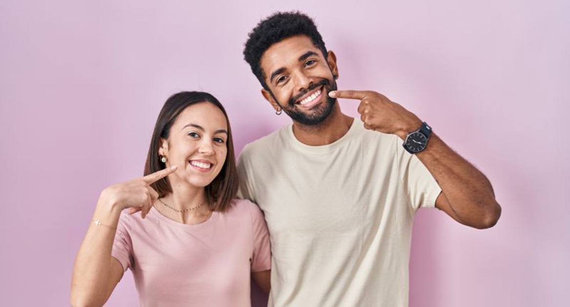 Happy couple pointing at their smiles