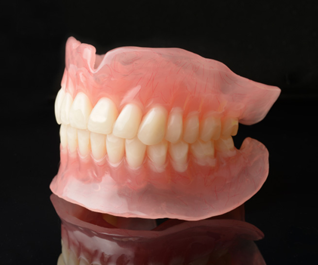 Full dentures in Beaverton on black reflective surface