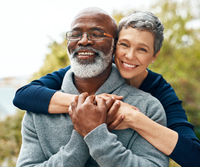 Senior woman hugging senior man from behind