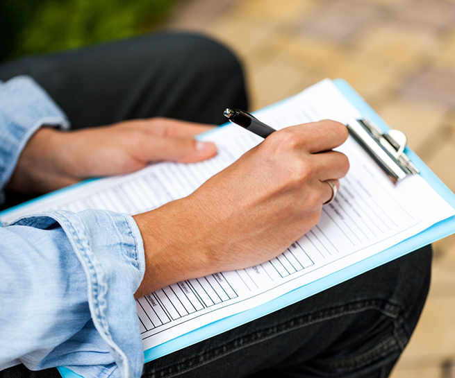 Person filling out paperwork on a clipboard