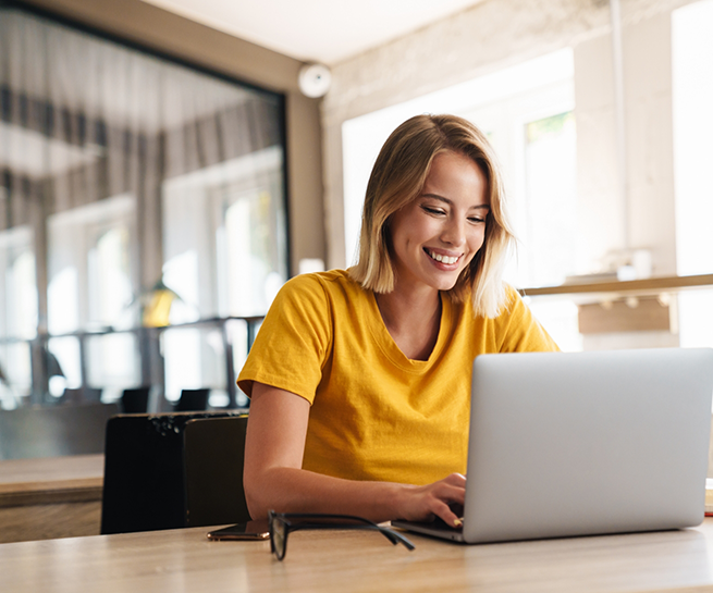 Smiling woman sitting at a table and using her laptop