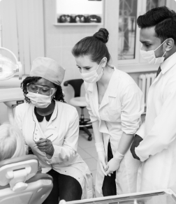 Three dental team members talking to a patient in the treatment chair