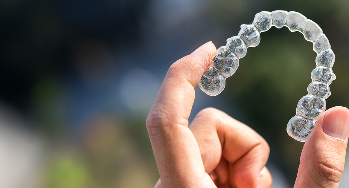 Close up of a hand holding an Invisalign clear aligner in Beaverton