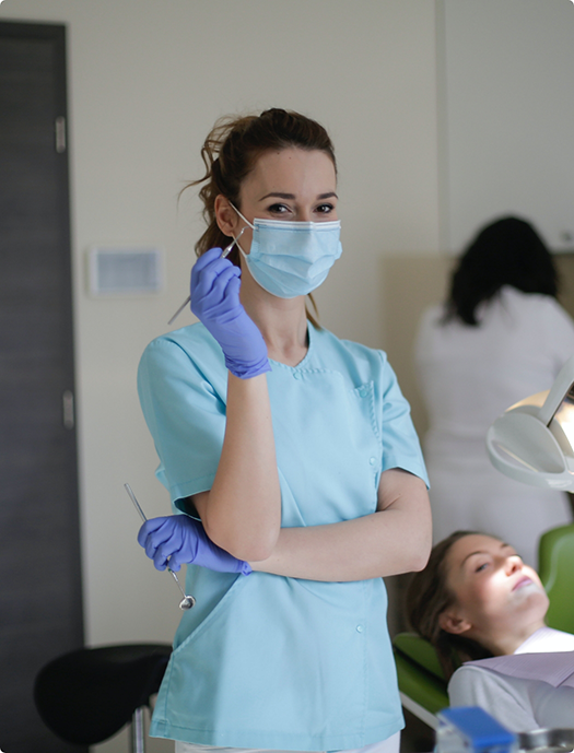 Doctor Appelhans wearing a face mask and scrubs and holding dental instruments