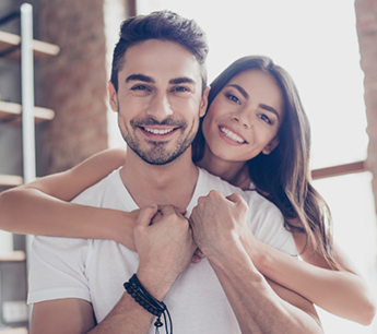 Young woman hugging a man from behind in their home