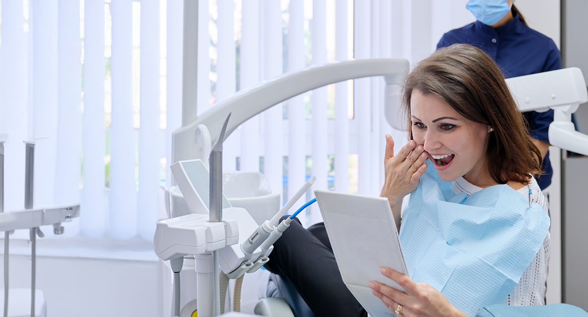 Dental patient looking at her new smile in a mirror after restorative dentistry in Beaverton