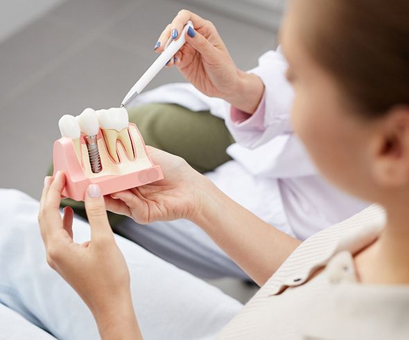 A dentist showing a patient a model of a dental implant