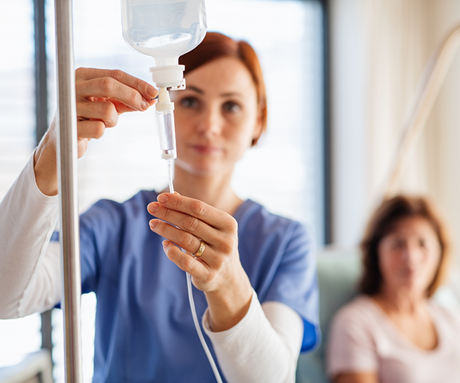 Woman in scrubs adjusting an I V drip