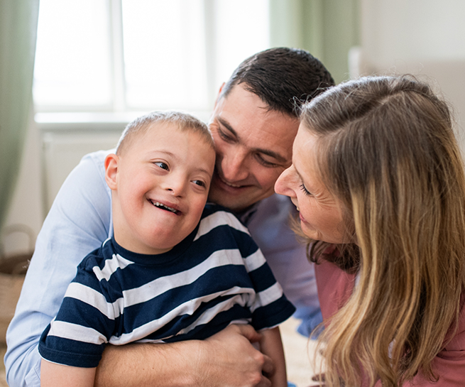 Mother and father hugging their young son with Down syndrome