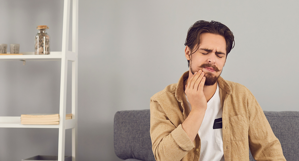 Man holding the side of his face in pain before tooth extractions in Beaverton