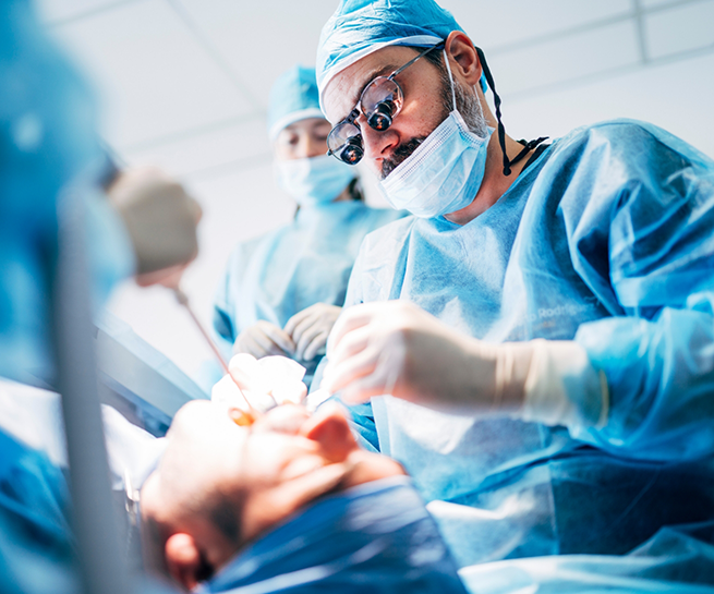 Dentist and team members performing wisdom tooth extractions on a patient
