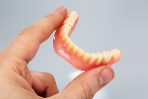 Close-up of dentures held between fingers