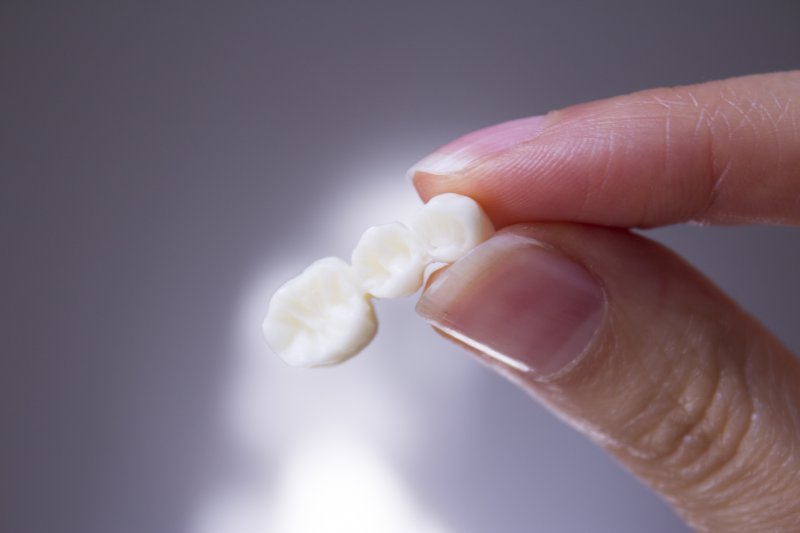 A dental bridge held between a thumb and finger