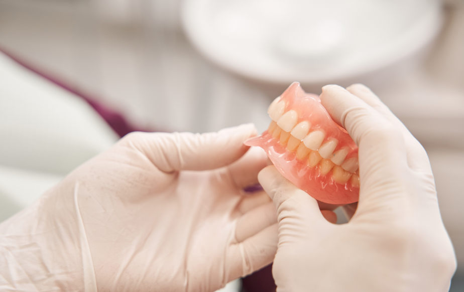 Gloved hands holding dentures